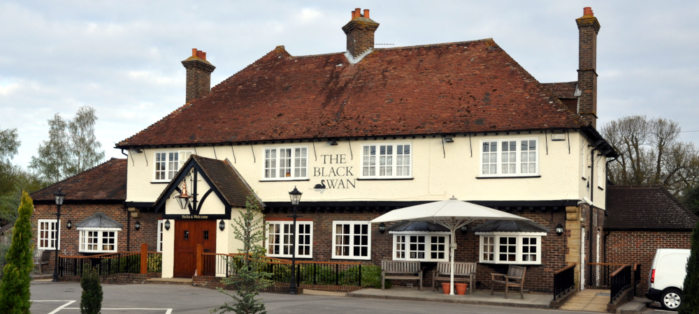 A two-storey brick building with the first floor rendered in yellow and the words The Black Swan
