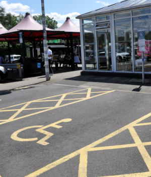 An area of tarmac with yellow markings: cross-hatched lines to each side, and a representation of a person sitting in a wheelchair